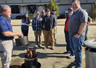 Gallery 67 Group of people gathered outdoors for a cooking demonstration at Automated Dynamics Corp. event.