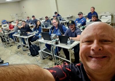 Gallery 68 Group of people in a classroom with laptops, instructor taking selfie, focused on training session.