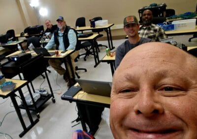 Gallery 77 Group of people in a classroom with laptops, smiling, taking a selfie.