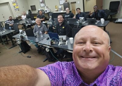 Gallery 95 Group of professionals in a training room with computers, smiling for a selfie.
