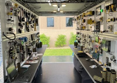 Gallery 12 Automated Dynamics Corp. mobile control room with electronic equipment and monitors.