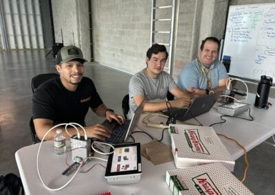 Gallery 18 Team of three people working on laptops at a table in an industrial office space.