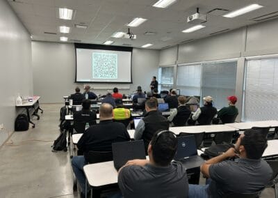 Gallery 21 Attendees in a classroom attending a presentation with a QR code on the screen at Automated Dynamics.
