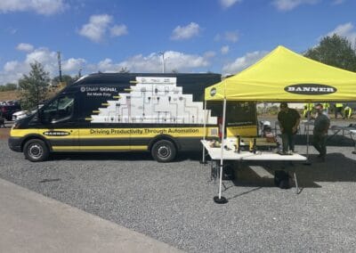 Gallery 23 Automated Dynamics Corp. mobile demo van with yellow tent at outdoor event, showcasing automation.