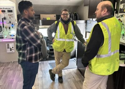 Gallery 25 Three men in safety vests having a discussion inside an electronics store or office.