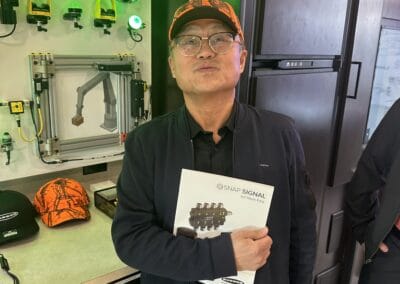 Gallery 32 Man holding product brochure at Automated Dynamics Corp. booth with safety solutions display.