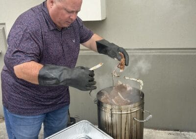 Gallery 41 Man grilling meat outdoors with a smoker and disposable tray, in a casual setting.