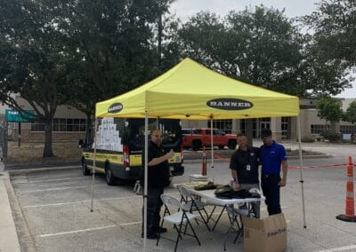 Gallery 45 Automated Dynamics Corp. outdoor event setup with yellow tent and staff in parking lot.