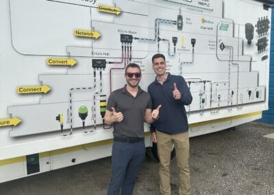 Gallery 57 Two men standing in front of a large technical diagram on a mobile unit at Automated Dynamics Corp.