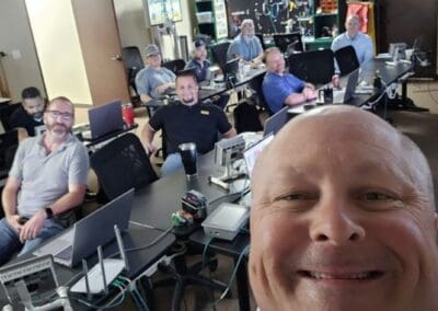 Gallery 4 Group of people in a training room with computers and technical equipment, smiling at the camera.