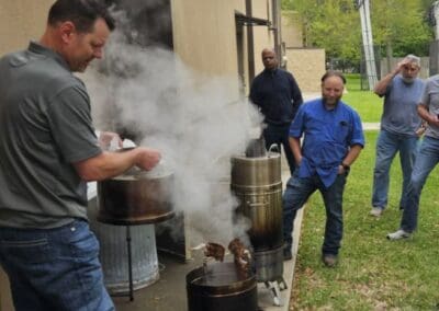 Gallery 5 Group of men observing a cooking demonstration outdoors at Automated Dynamics Corp. Gallery.